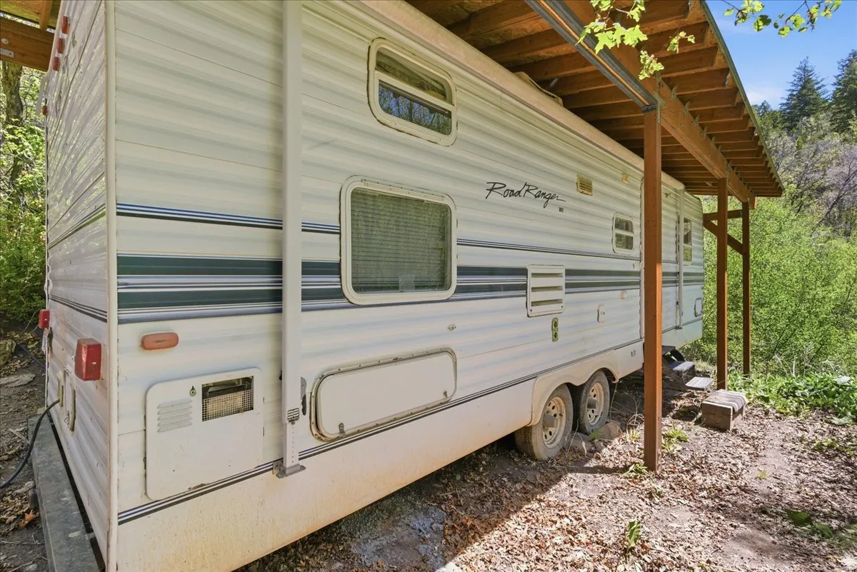 Travel trailer with a side awning, dual axles, and a dedicated covered shelter