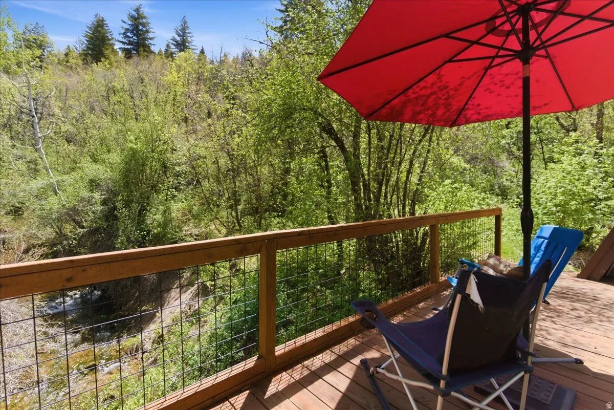 Wood deck featuring a wire mesh railing and natural treeline backdrop