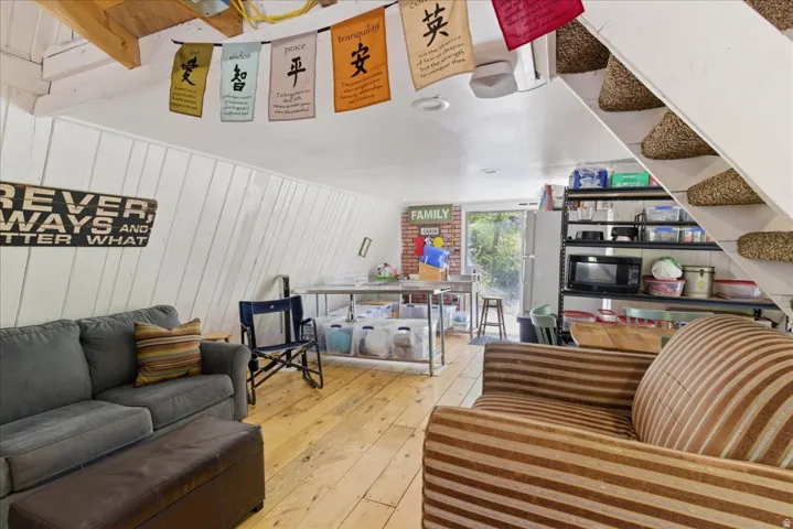 Spacious room with sloped white wood-paneled walls and wood-finish flooring