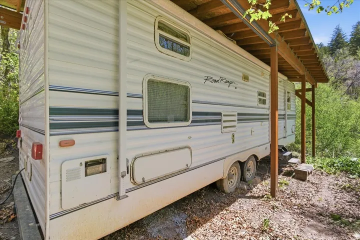 Travel trailer with a side awning, dual axles, and a dedicated covered shelter