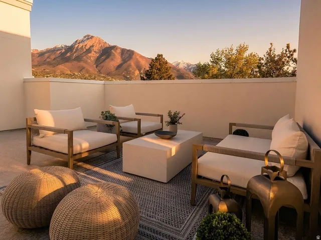 Expansive outdoor terrace featuring a concrete surface, low cream-colored perimeter walls, and a prominent mountain backdrop