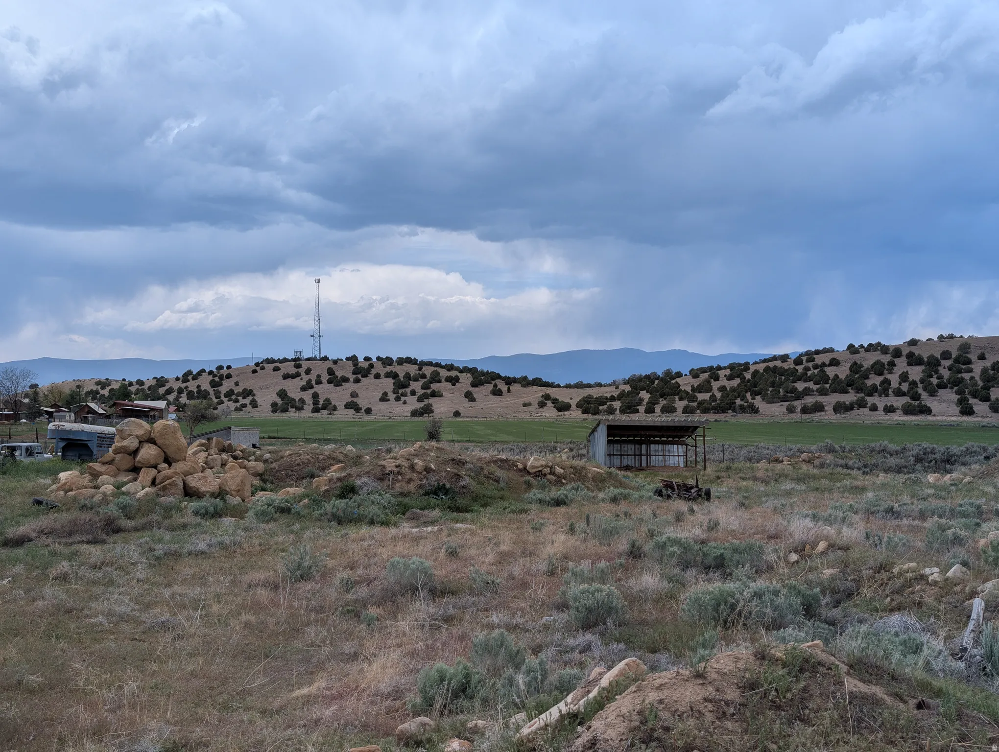 Expansive rural landscape featuring rolling hills with scattered vegetation and distant mountains