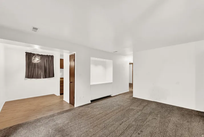 Open living area featuring neutral wall tones and dark carpeting