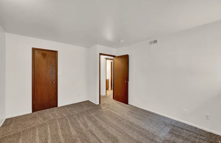 Spacious room featuring neutral carpeting, white walls, and a white ceiling