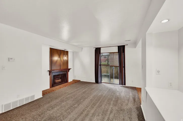 Living space featuring a wood-paneled fireplace with a brick hearth, wall-mounted chandelier, and recessed lighting