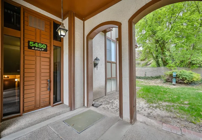 Entryway featuring a wood-paneled door with sidelight windows, covered concrete porch, and arched architectural details