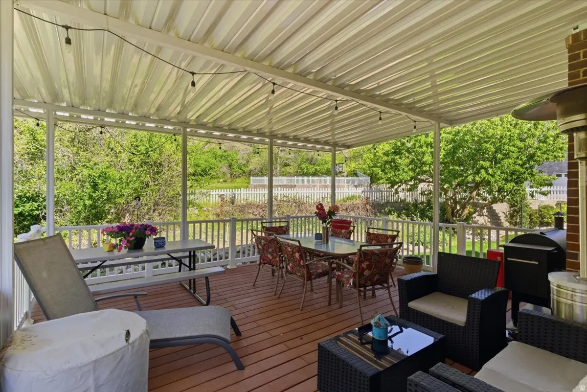 Expansive outdoor deck featuring a white metal patio cover, string lighting, and white railings