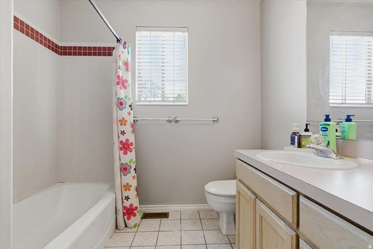 Bathroom featuring a single vanity with a laminate countertop, an integrated sink, and wood-finish cabinetry