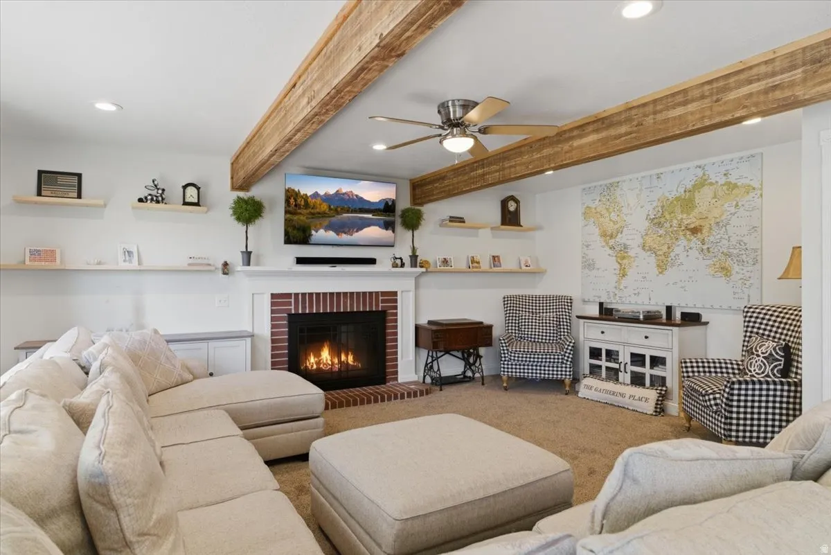 Spacious living area featuring exposed wood beams, recessed lighting, and a brick-surround fireplace with a white mantel