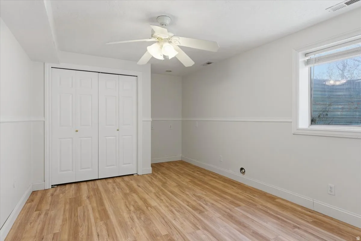 Room featuring wood-finish flooring, crisp white walls, and wainscoting
