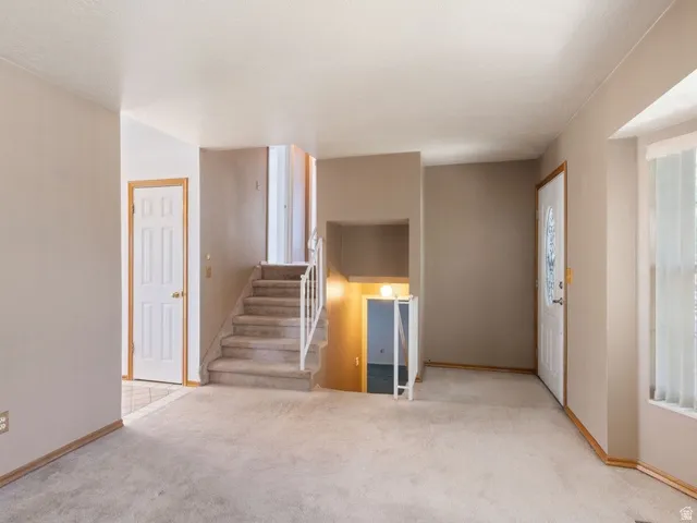 Entryway featuring a decorative glass front door, staircase with carpeted treads, and light beige wall paint