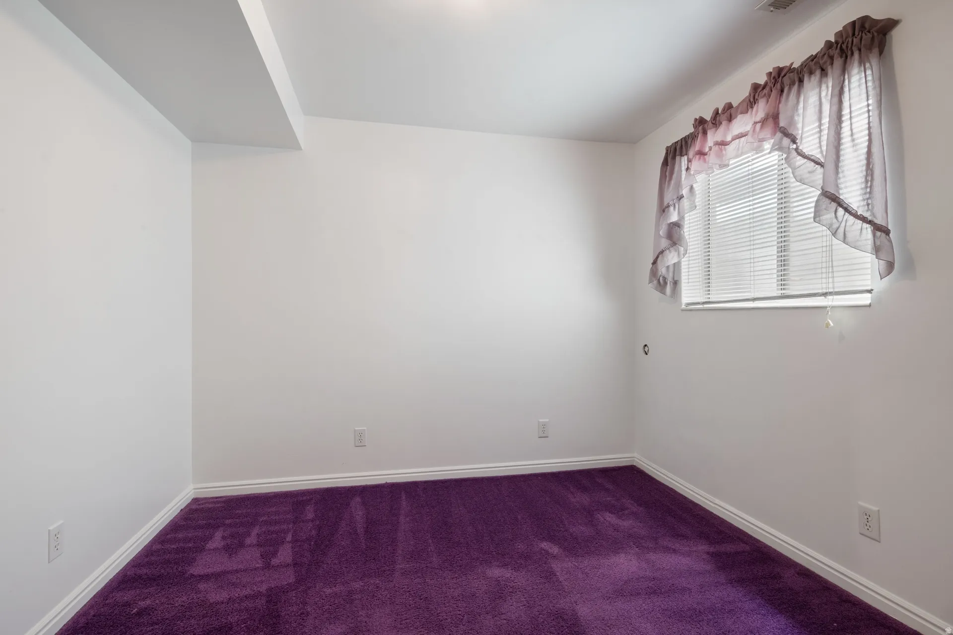 Room featuring white walls, bright purple carpeting, and a single window with horizontal blinds