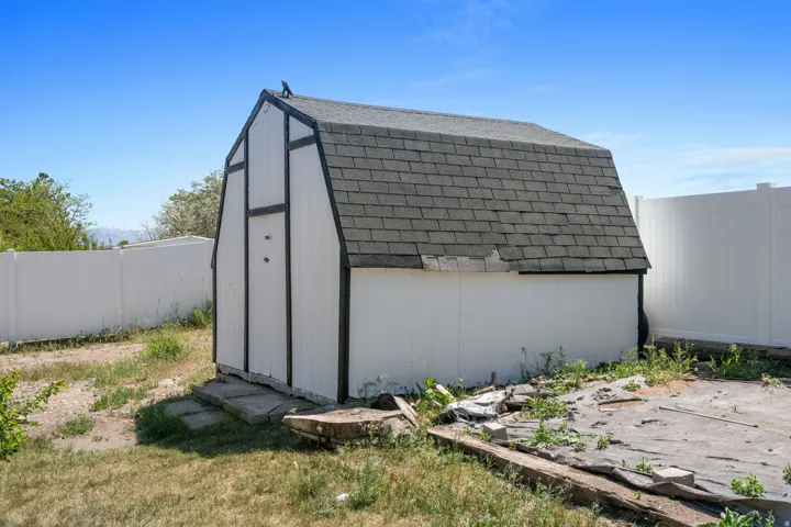 Utility shed featuring a gambrel roof and white siding with dark trim