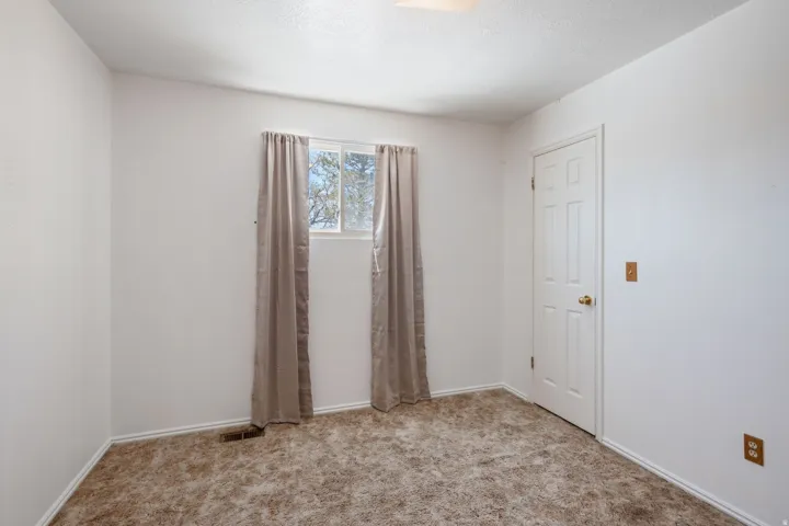 Room featuring a rectangular window, light brown carpet, and a paneled white door