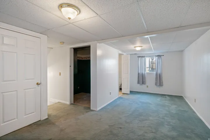 Spacious room with light blue carpeting, white walls, and a drop ceiling