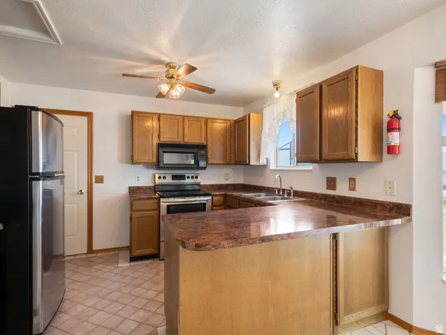 Kitchen featuring wood cabinetry, stainless steel appliances, a U-shaped countertop with a breakfast bar extension, and tiled flooring