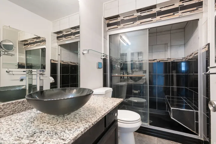 Bathroom featuring a vessel sink, granite-finish countertop, and a shower with sliding glass doors
