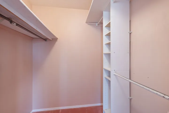 Closet featuring a built-in shelving unit, dual clothing rods, and wall-mounted shelving