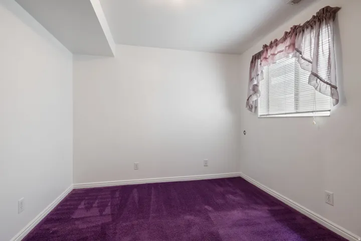 Room featuring white walls, bright purple carpeting, and a single window with horizontal blinds