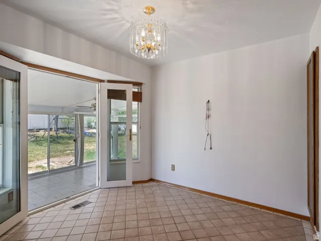 Room featuring a crystal chandelier, tile flooring, and white walls