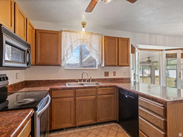 Kitchen featuring wood-finish cabinetry, a double basin sink, and an integrated dishwasher