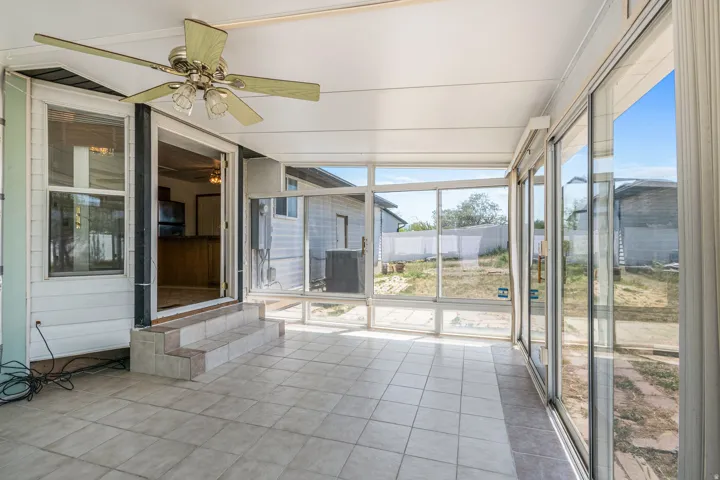 Sunroom featuring tile flooring, a ceiling fan, and extensive window panels