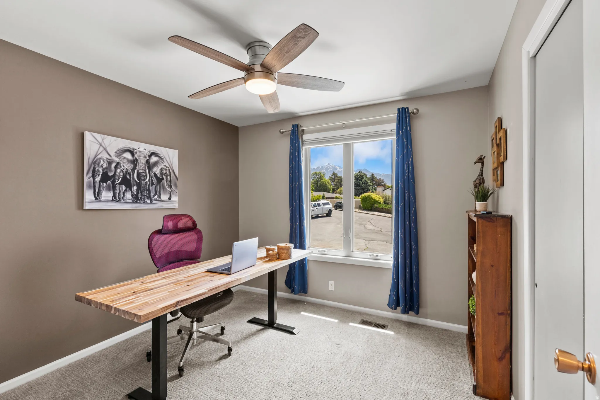 Bright room featuring a large window, neutral carpeting, and a ceiling fan with integrated lighting