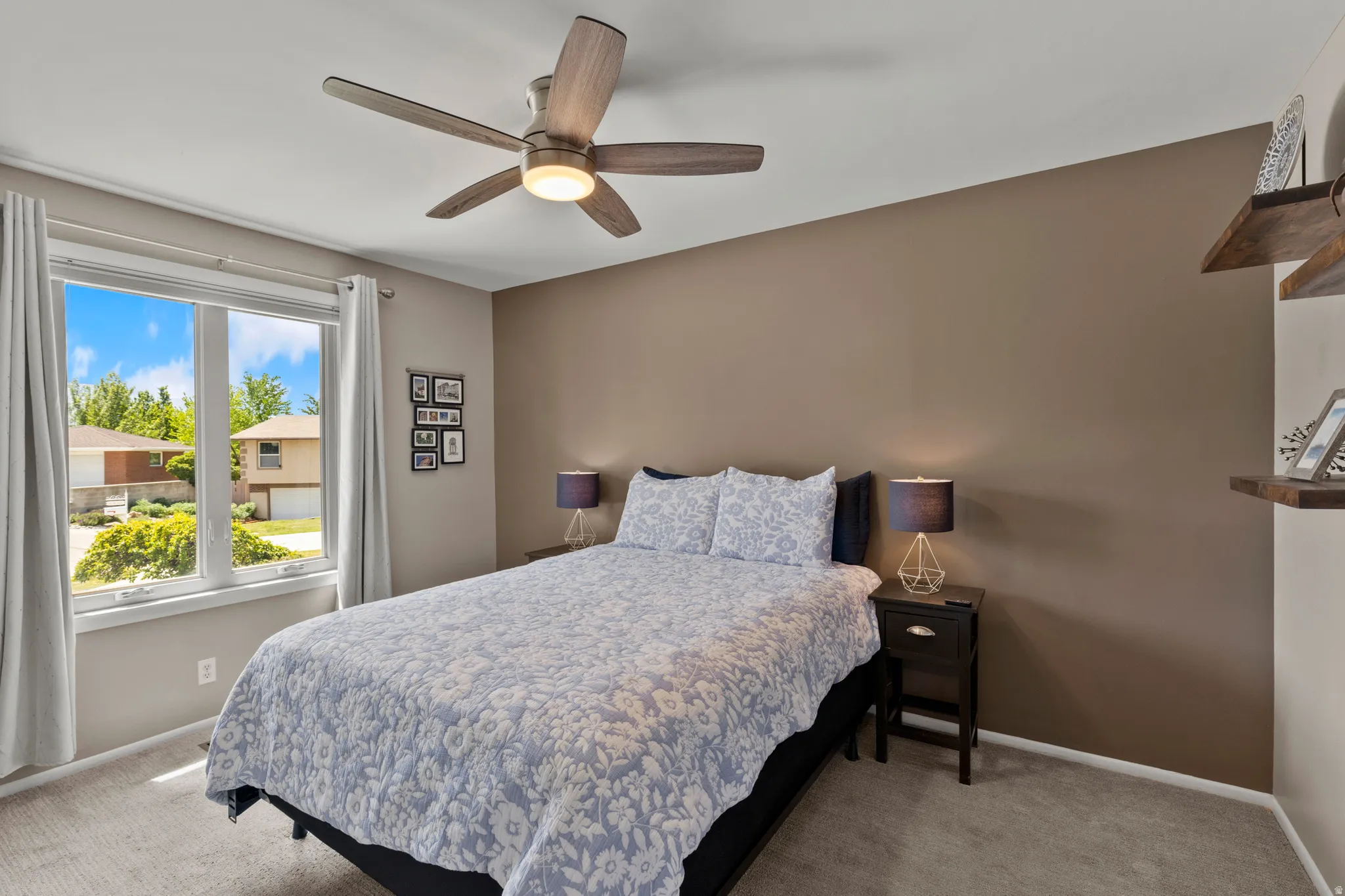Bedroom featuring a large window, neutral wall paint, a built-in ceiling fan with light, and carpet flooring