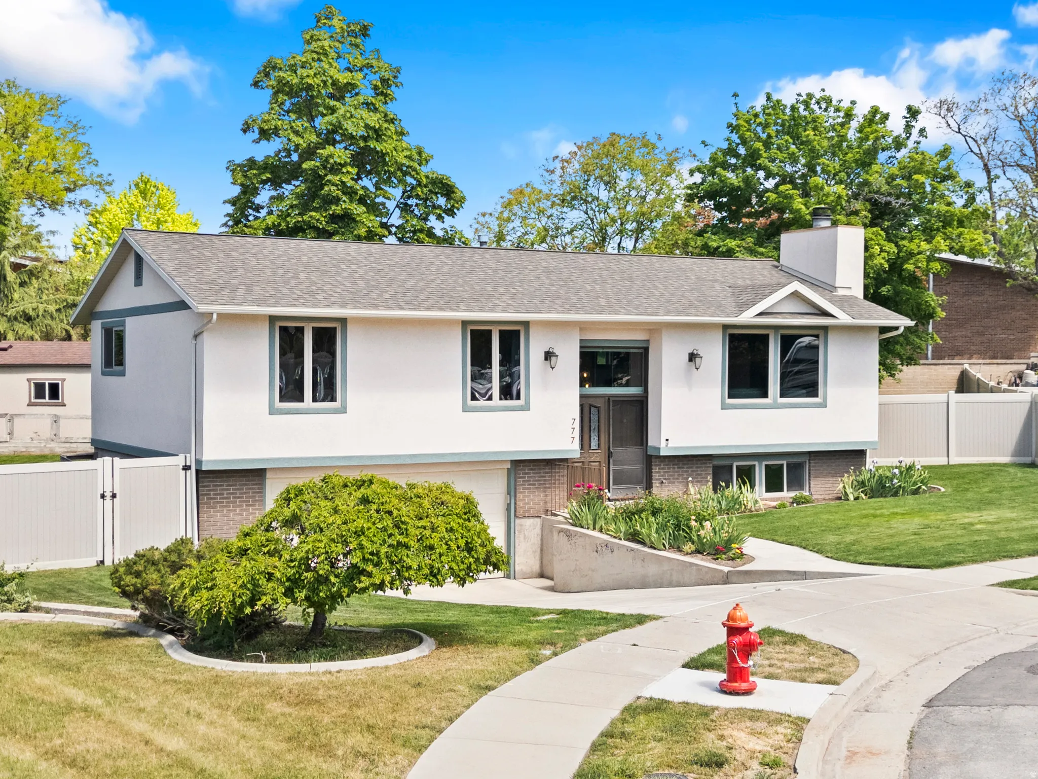 Split-level residence featuring a white facade with contrasting trim, a gabled roofline, and brick accents on the lower level