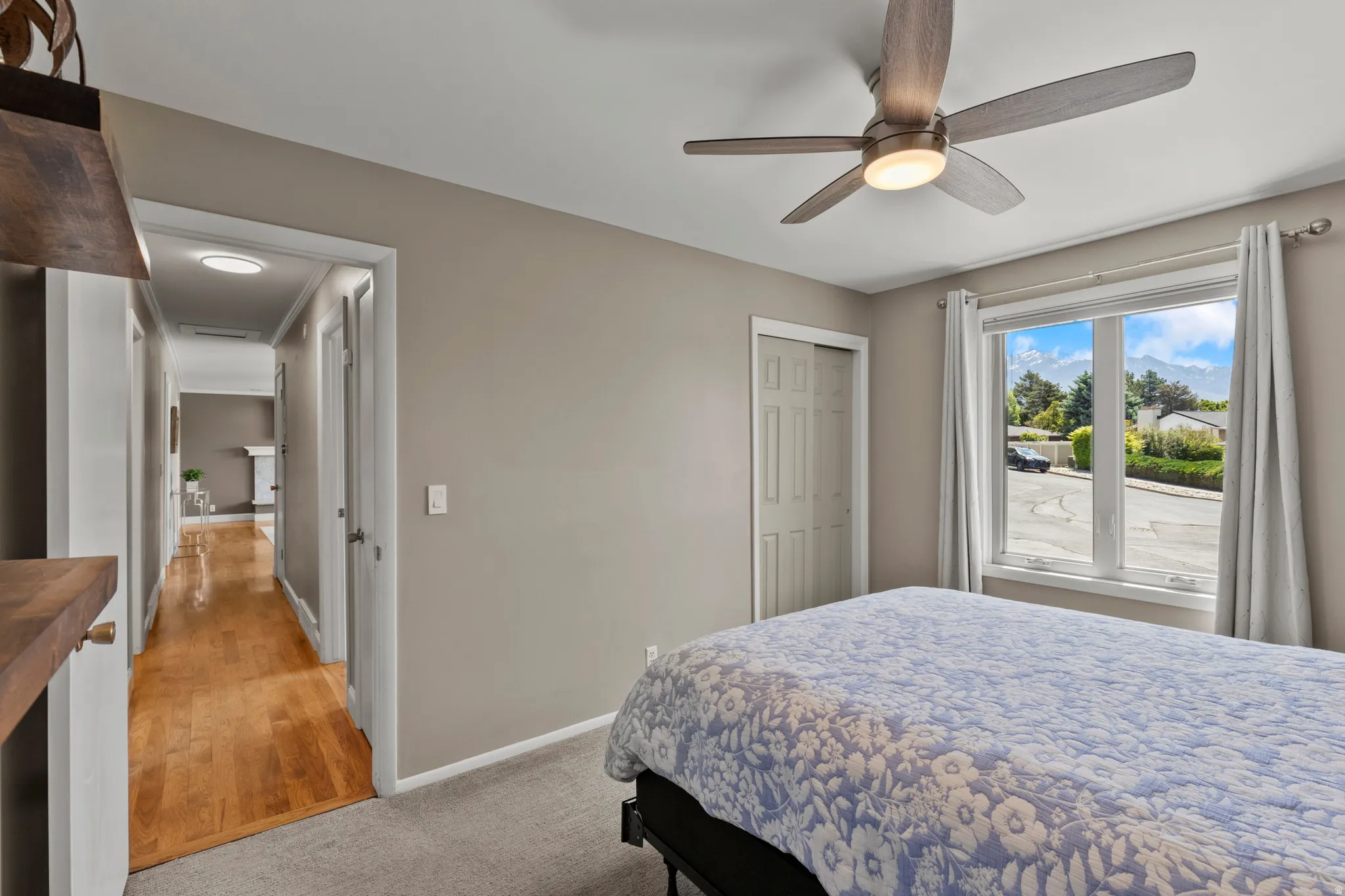 Bedroom featuring neutral tone walls, soft carpeting, a ceiling fan with integrated lighting, a multi-pane window, and a paneled closet door
