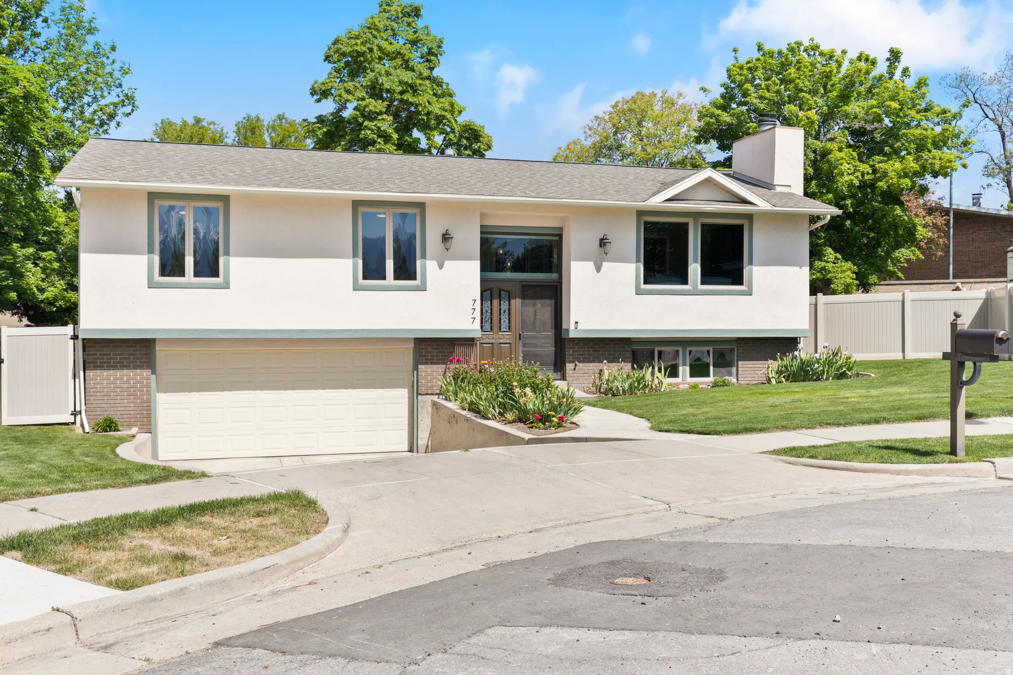 Split-level residence featuring a two-car garage, stucco exterior, and a prominent front door with sidelights