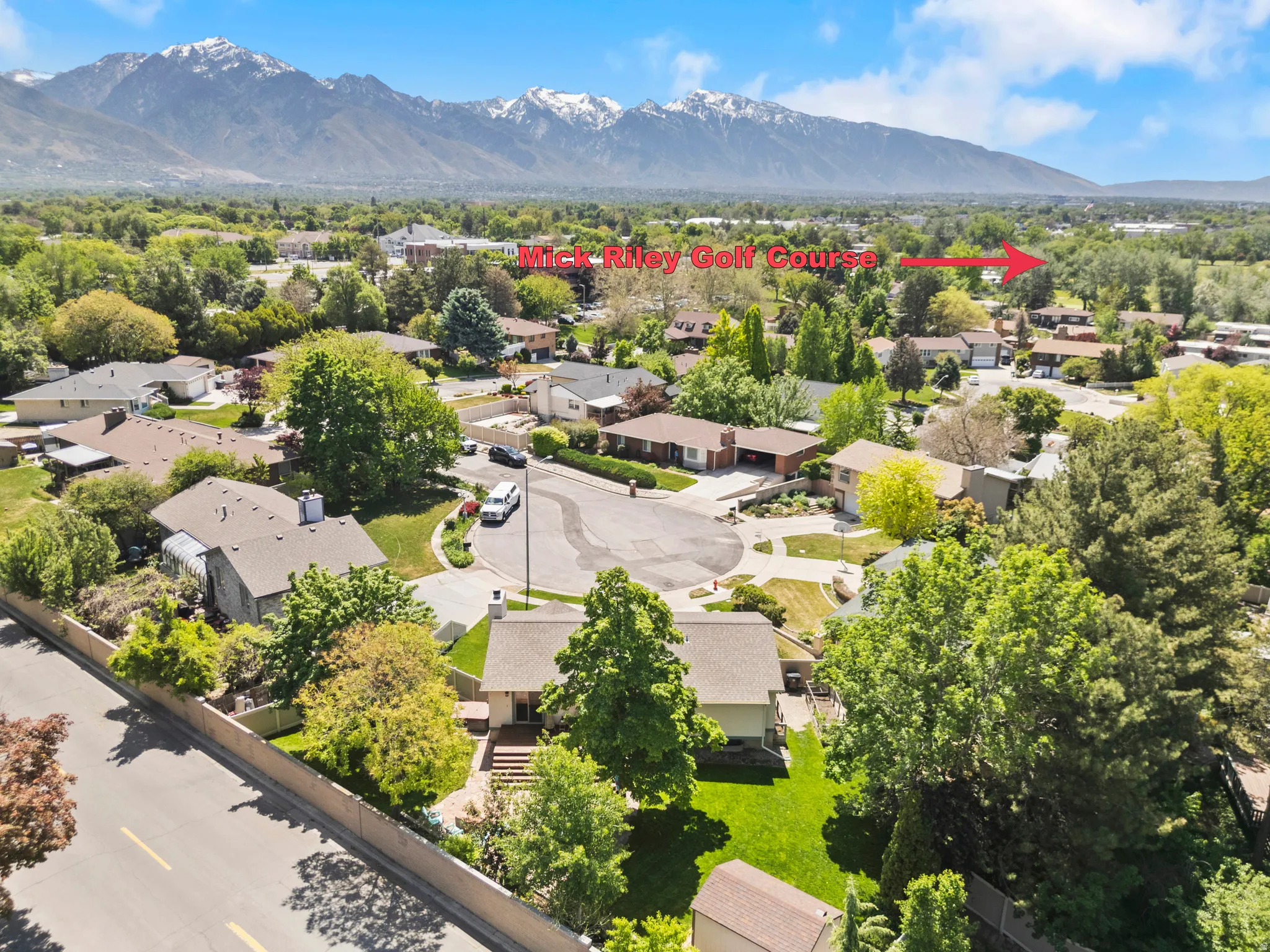 Residential neighborhood setting with mature trees and mountain backdrop