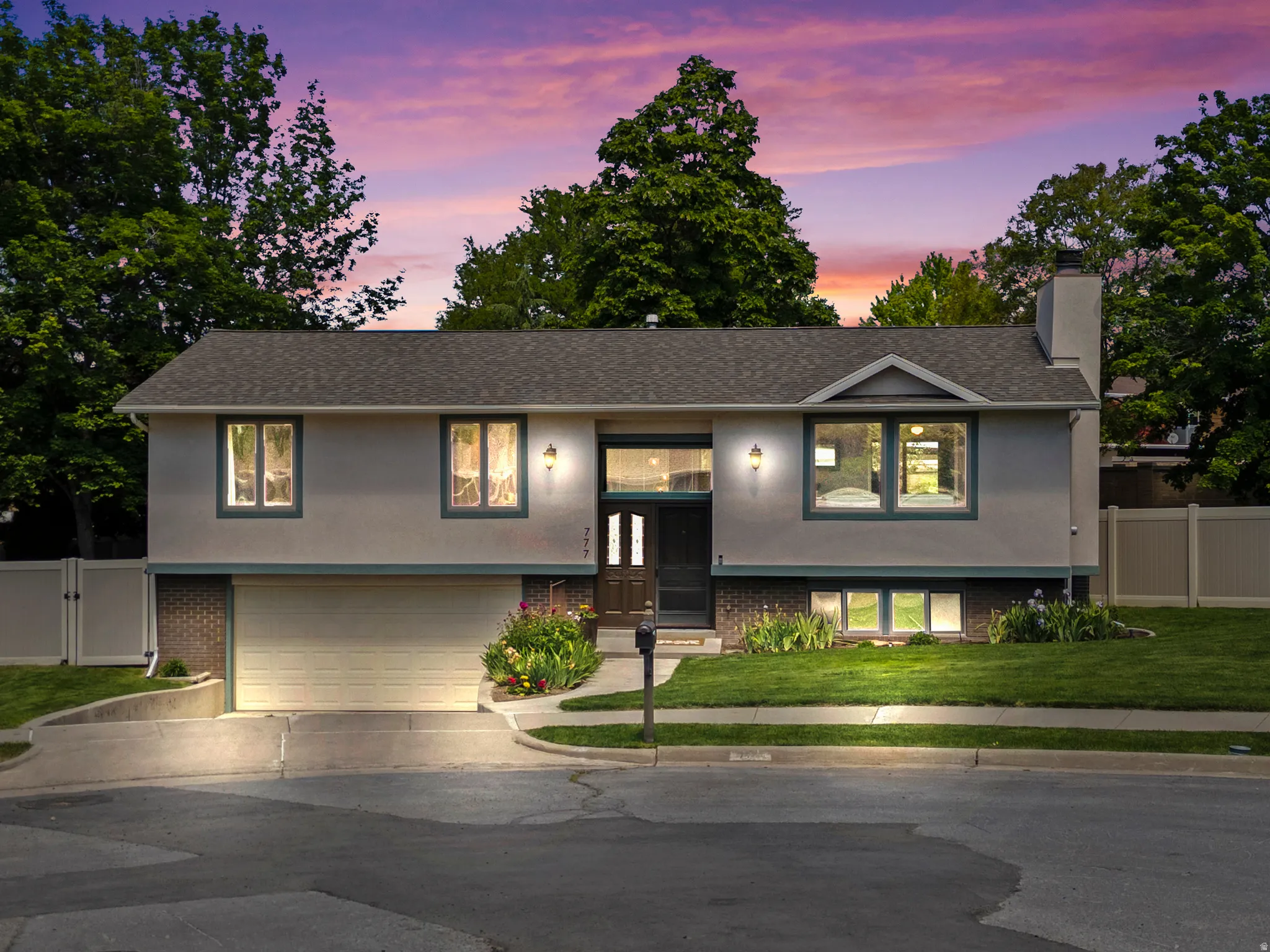 Split-level residence featuring a stucco and brick exterior, asphalt shingle roof, and an attached two-car garage