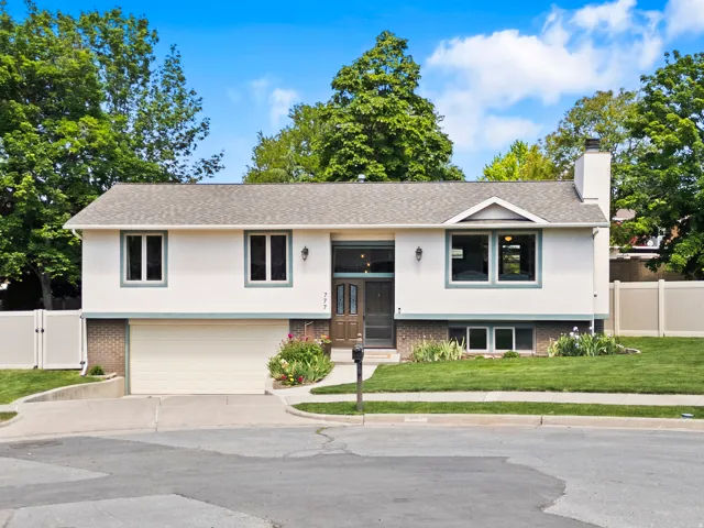 Split-level residence featuring a two-car garage, stucco exterior with brick accents, and a prominent front entry with sidelights