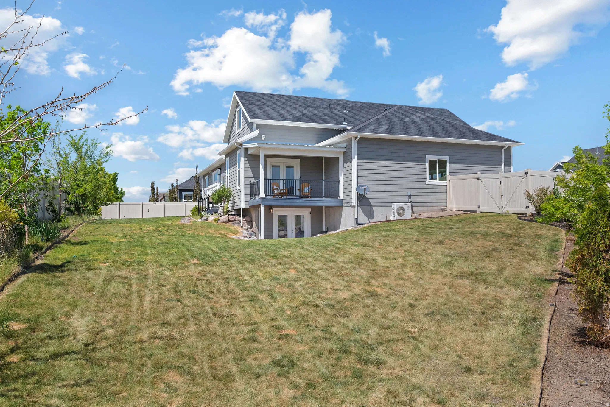 Expansive rear yard featuring a sloped lawn and mature perimeter landscaping