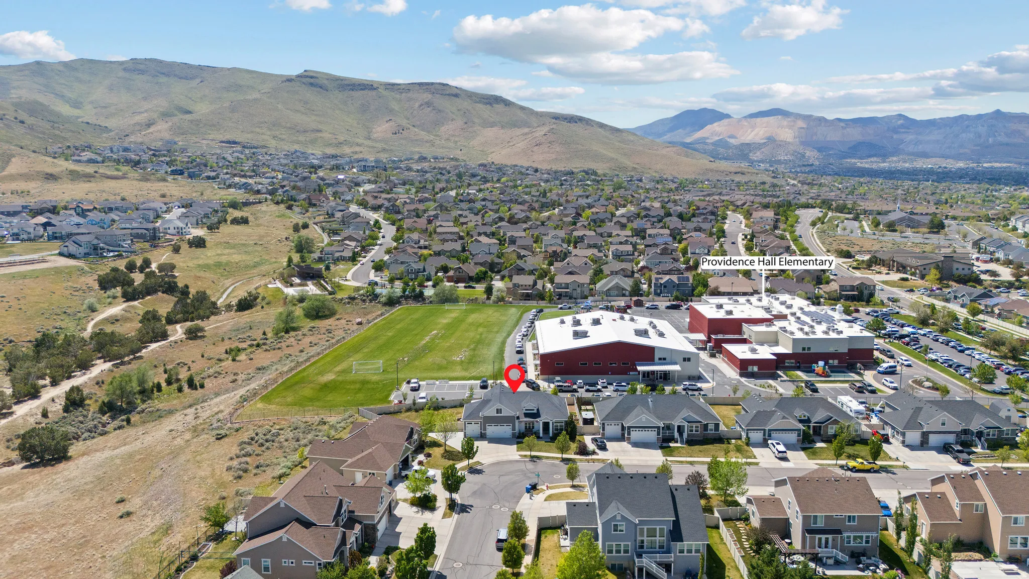 Aerial perspective showcasing a residential neighborhood with mountain backdrops, established homes, and manicured green spaces