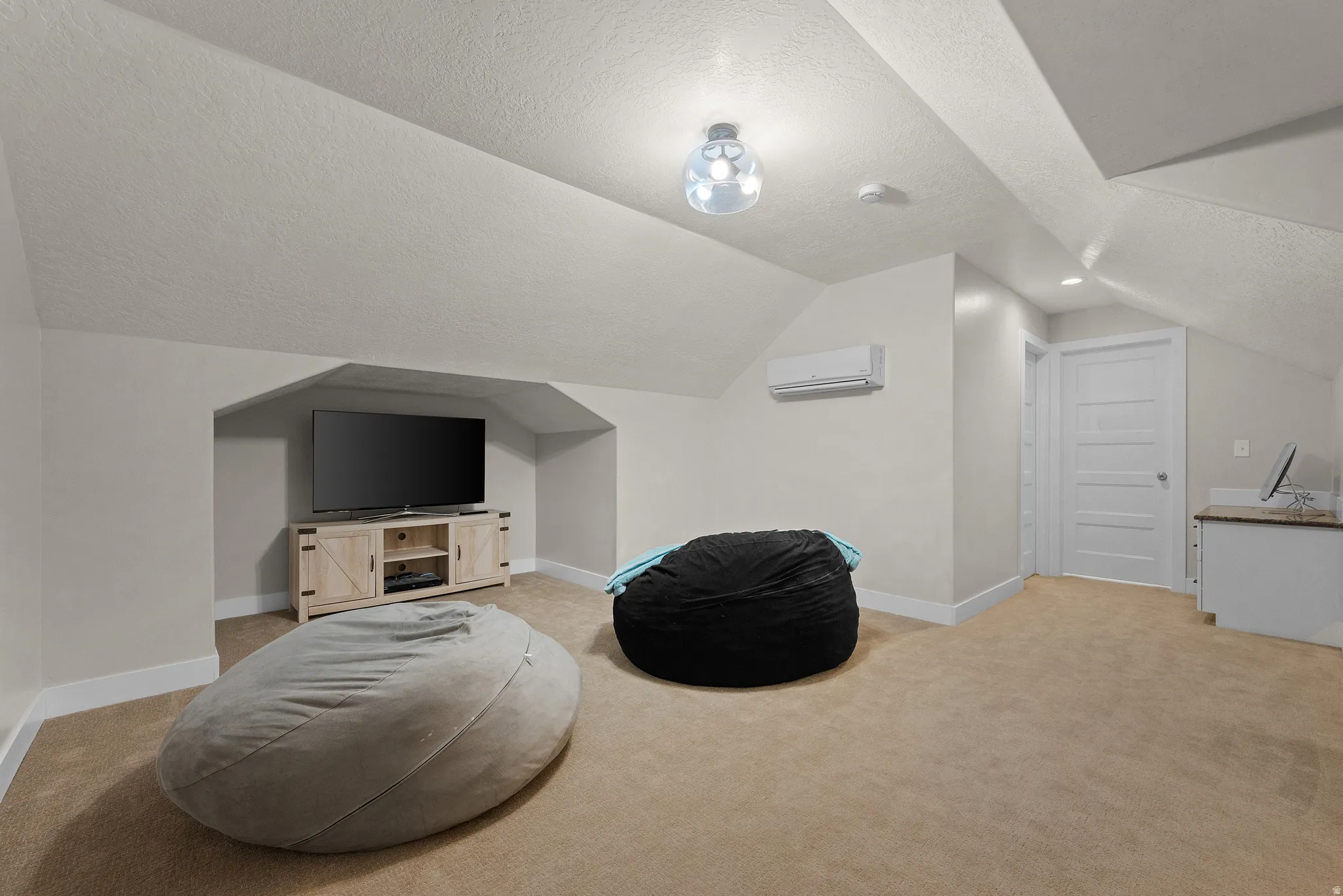 Carpeted bonus room featuring an integrated media niche, a mini-split HVAC unit, a built-in countertop with cabinetry, and a five-panel interior door