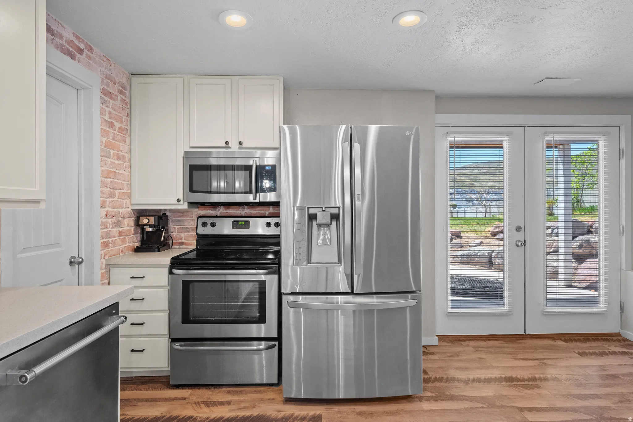Kitchen featuring wood-finish flooring, white cabinetry, and stainless steel appliances