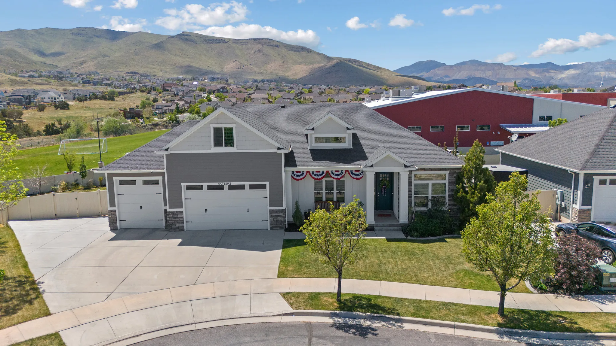 Contemporary ranch-style home featuring a two-car garage, gray siding, and stone accents