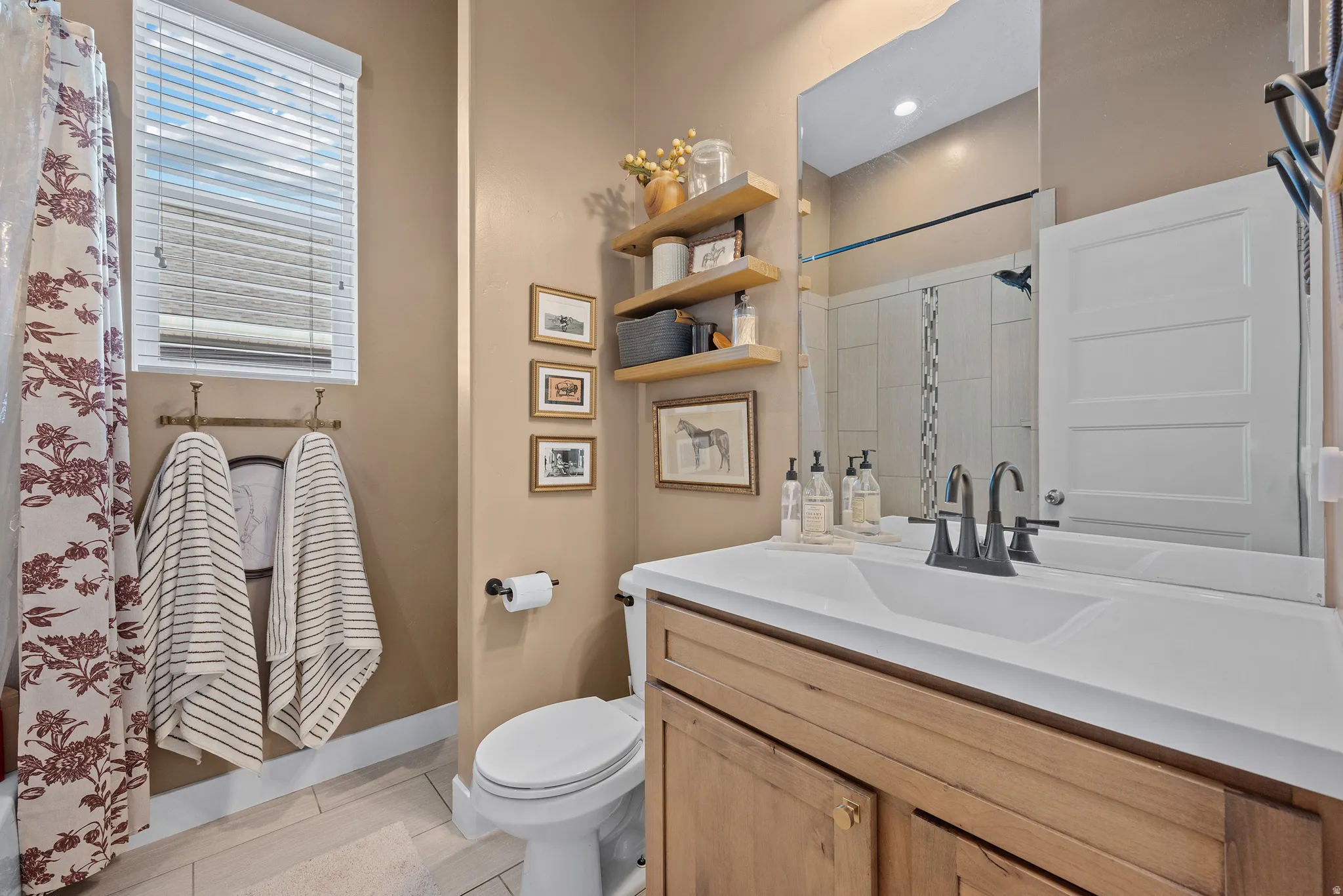 Bathroom featuring a wood-finish vanity with a white integrated sink and dark-finish faucet