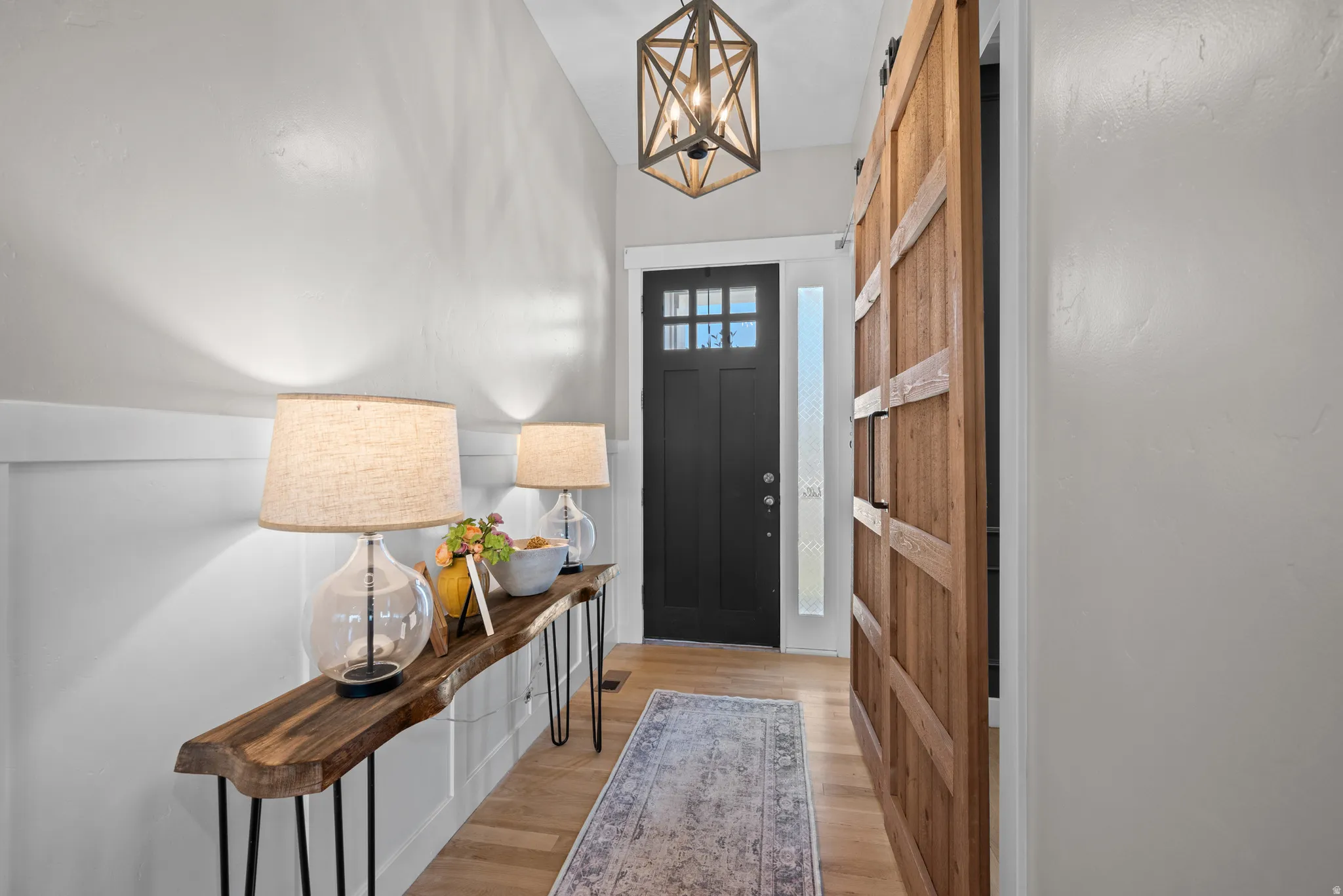 Entryway featuring light wood-finish flooring and a dark paneled door with glass inserts