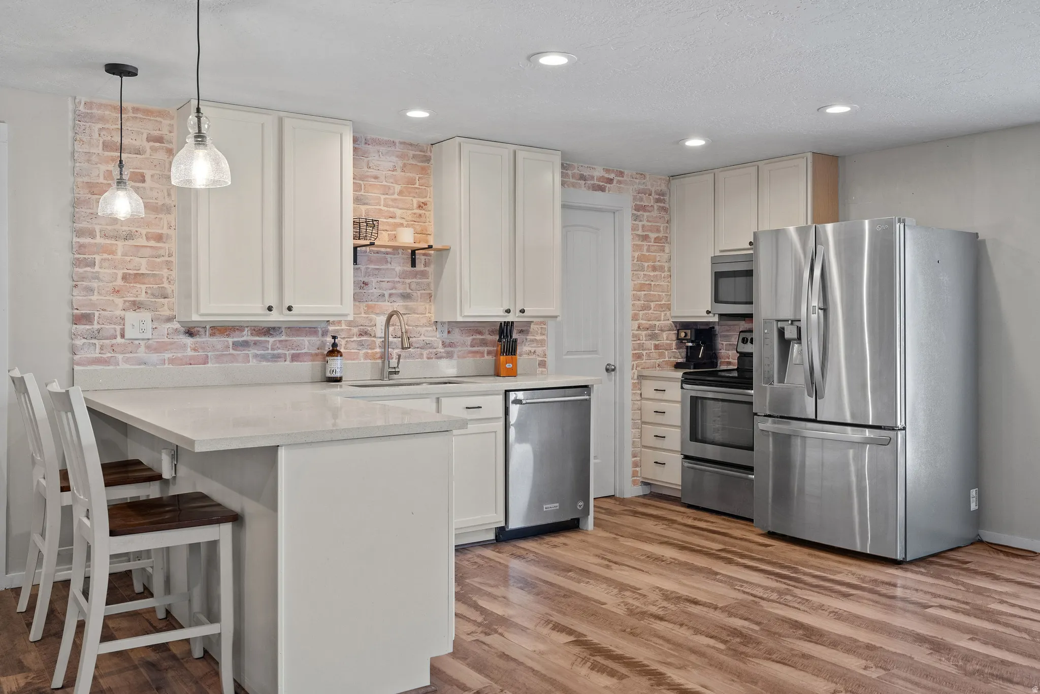Kitchen featuring wood-finish flooring, white cabinetry, and stainless steel appliances