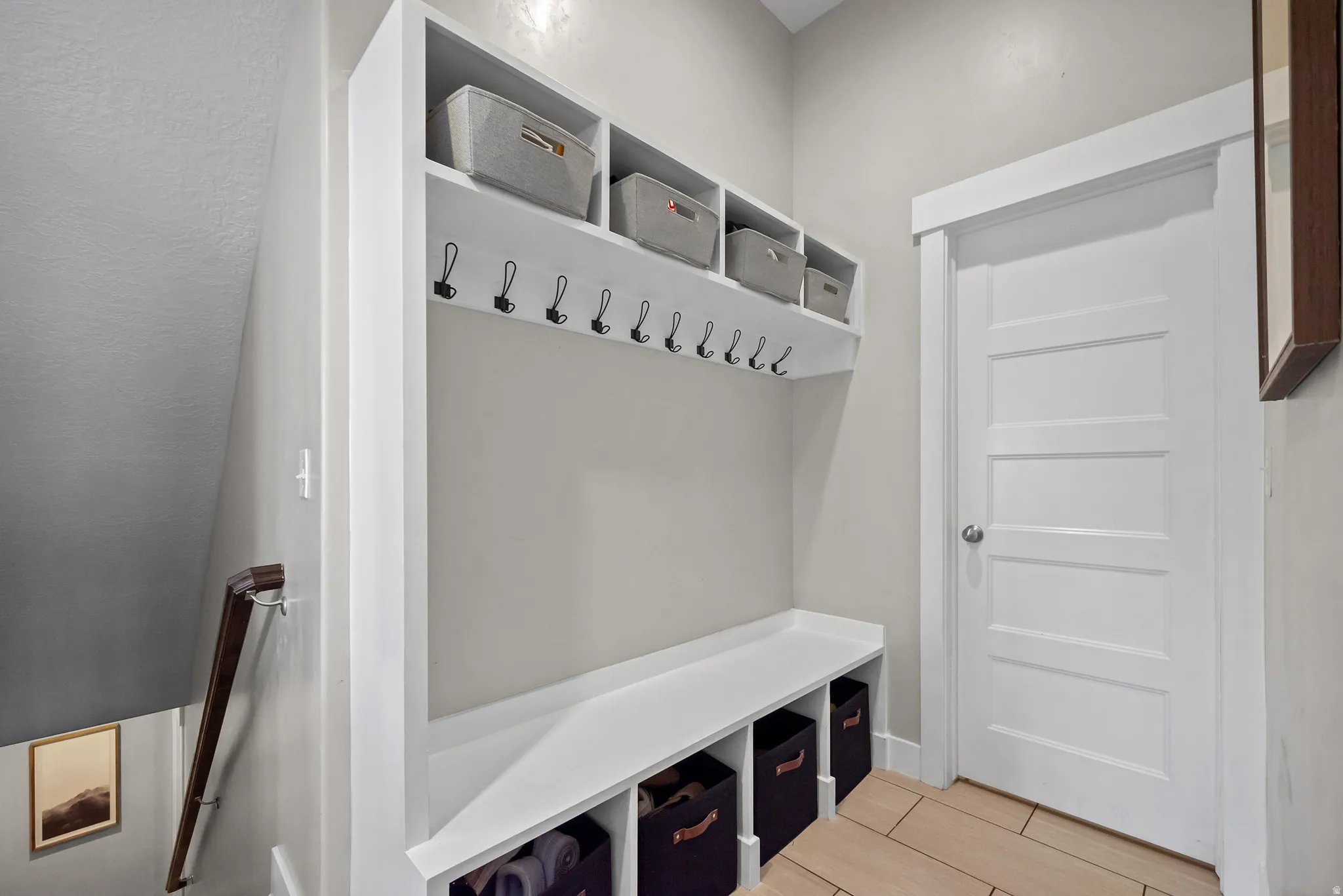 Built-in mudroom station featuring white cabinetry, integrated bench seating, and overhead shelving