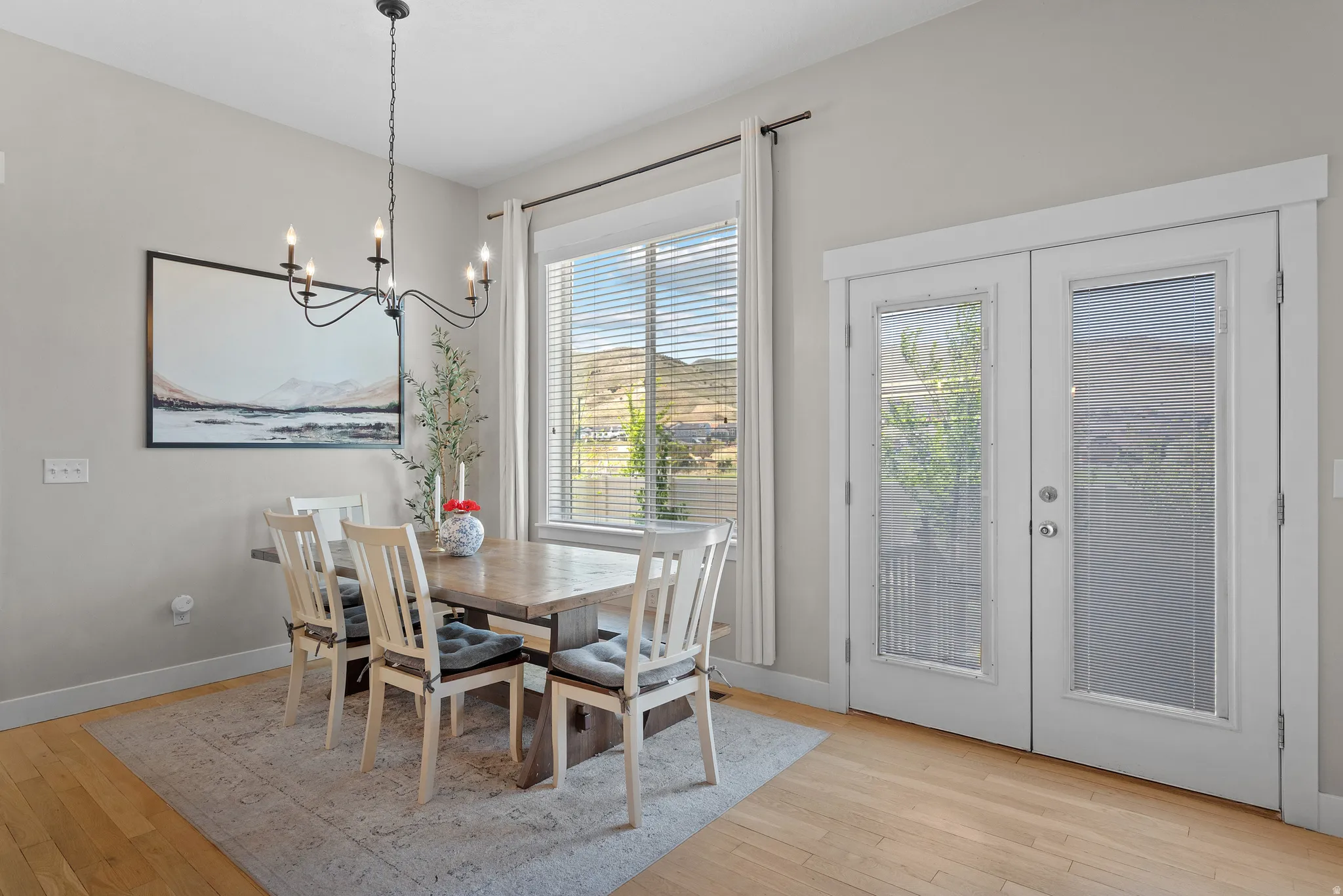 Dining area featuring light wood-finish flooring, a large window with blinds, and white French doors