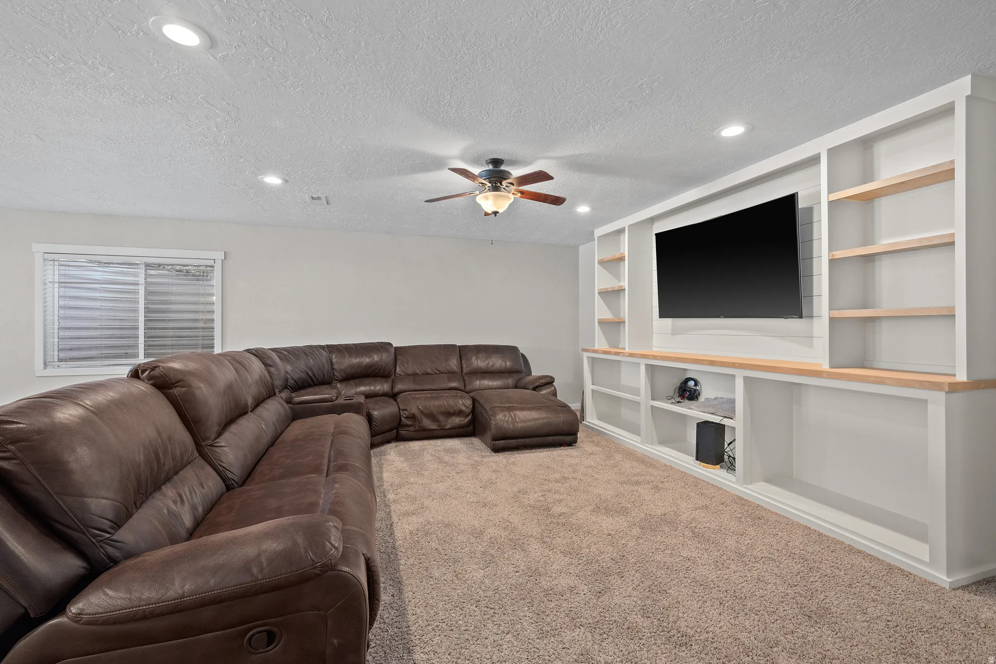 Integrated entertainment center with built-in shelving, wood-finish countertops, and a wall-mounted television