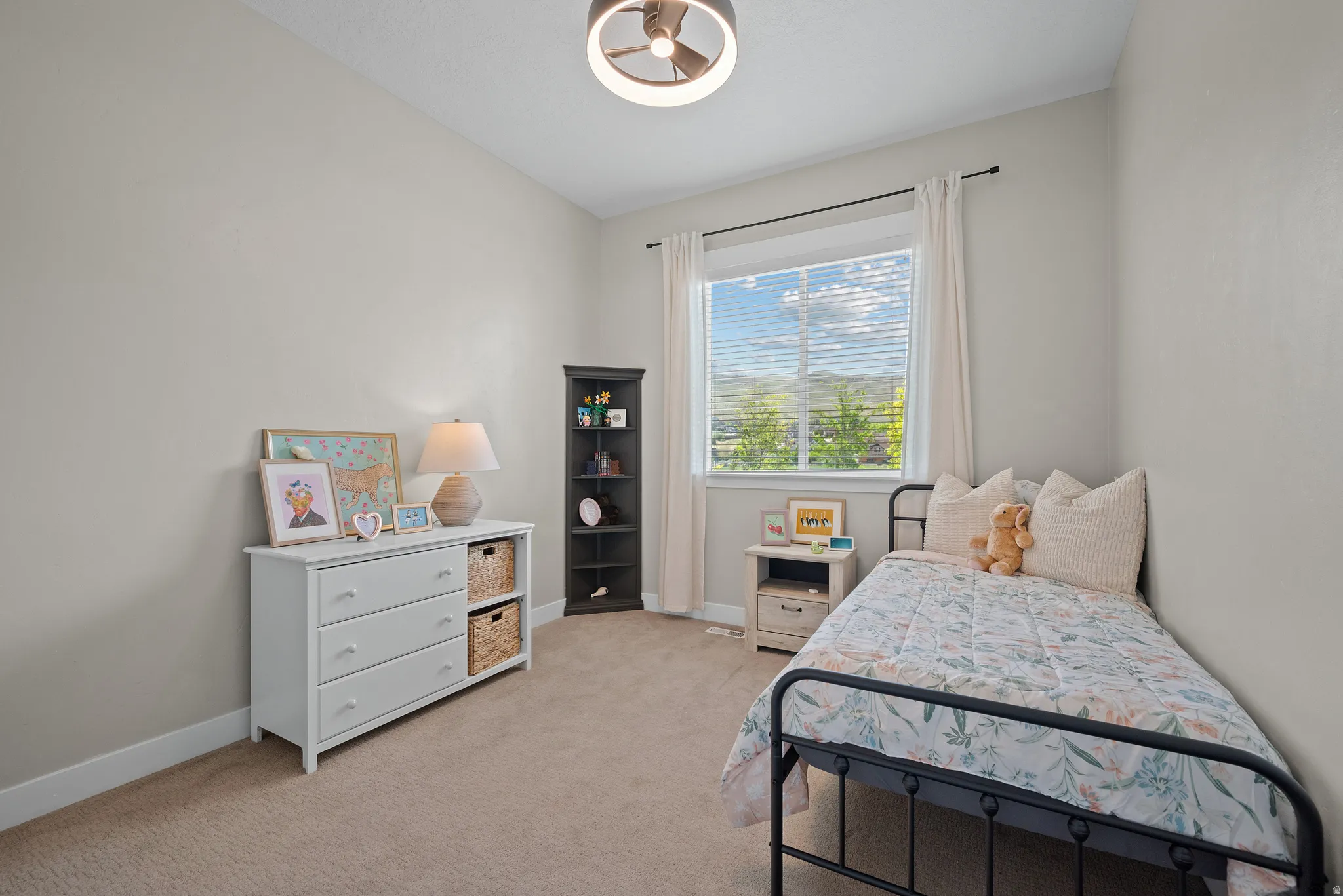 Carpeted bedroom featuring a large window with horizontal blinds, a modern ceiling fan with integrated lighting, and neutral wall tones