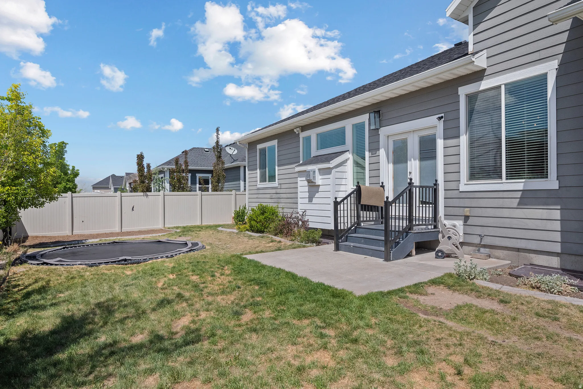 Rear exterior featuring gray siding, a private patio, and a staircase leading to double glass doors
