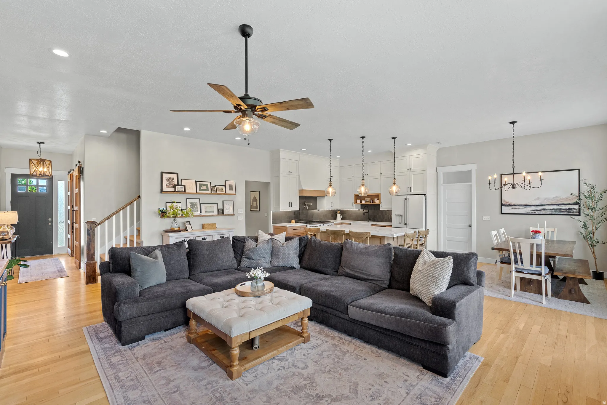 Open-concept living space featuring wood-finish flooring, a ceiling fan with light, and recessed lighting