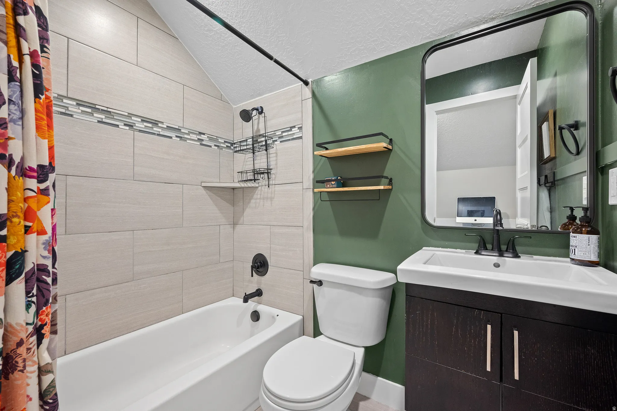 Bathroom featuring a tiled shower surround with accent band, a white tub, and matte black fixtures
