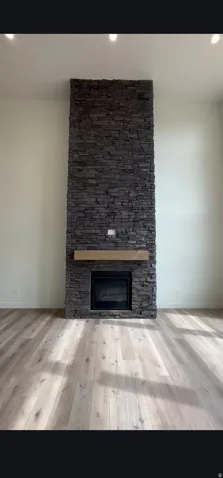 Floor-to-ceiling stacked stone fireplace featuring a wood mantel